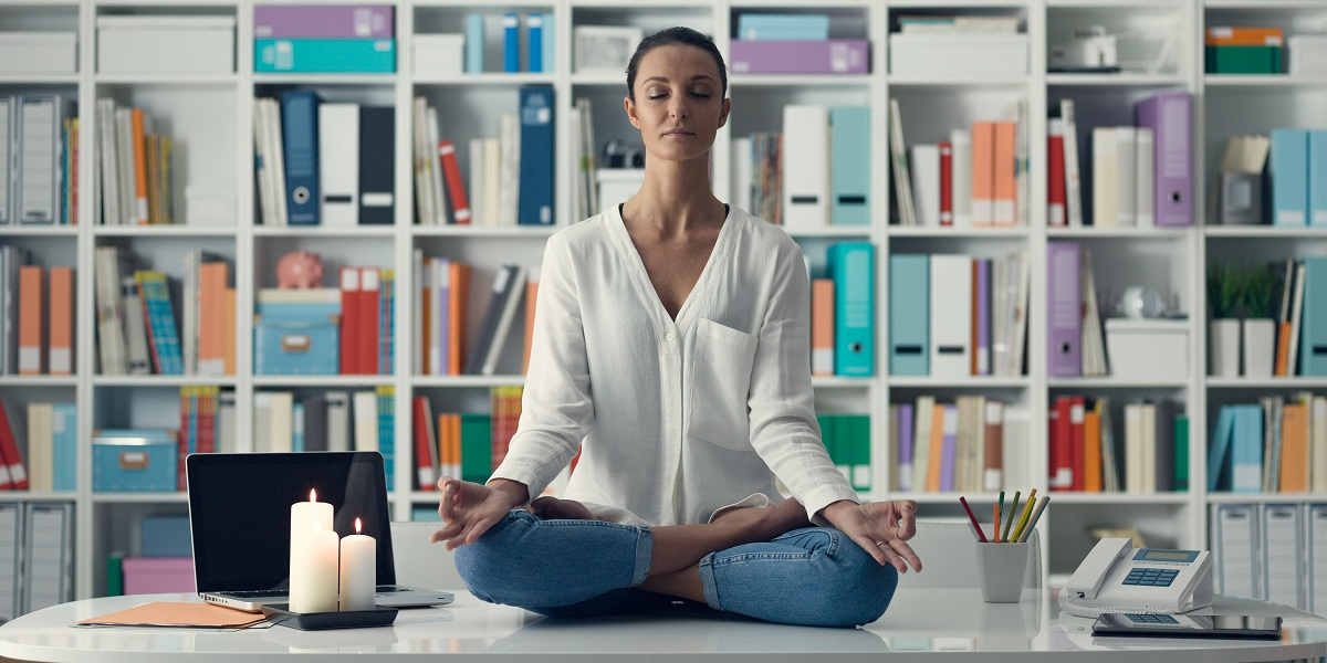 Donna che pratica meditazione alla scrivania in ufficio, simbolo di crescita personale ed equilibrio interiore