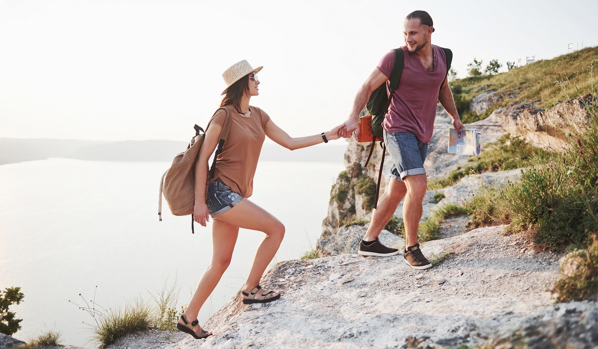 Coppia che si aiuta durante un'escursione in montagna, simbolo del percorso di crescita personale e del miglioramento passo dopo passo.